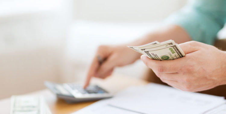 overtime for salaried worker close up of person with calculator counting money and making notes at home