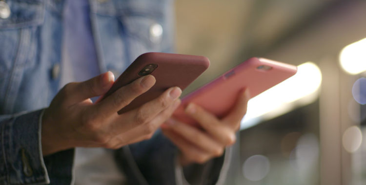 Busy woman using two mobile phone together