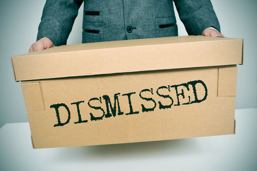 Picture of a man in a suit holding a cardboard box with DISMISSED printed on it