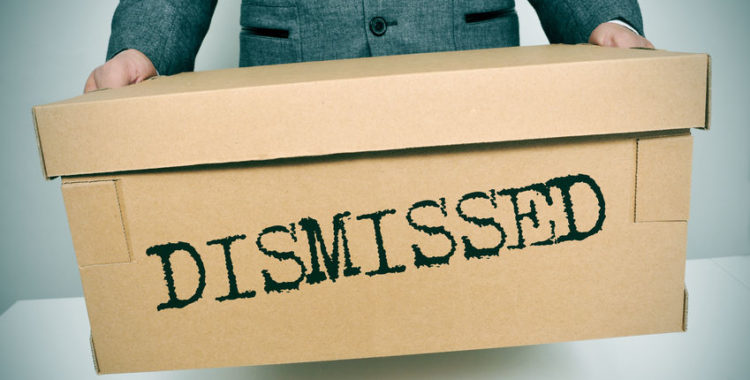 a businessman carrying a box with the word dismissed written on it