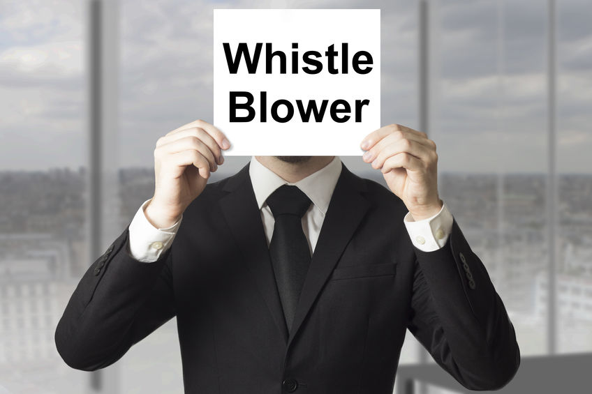 Picture of a man in a suit holding a whistleblower sign in front of his face