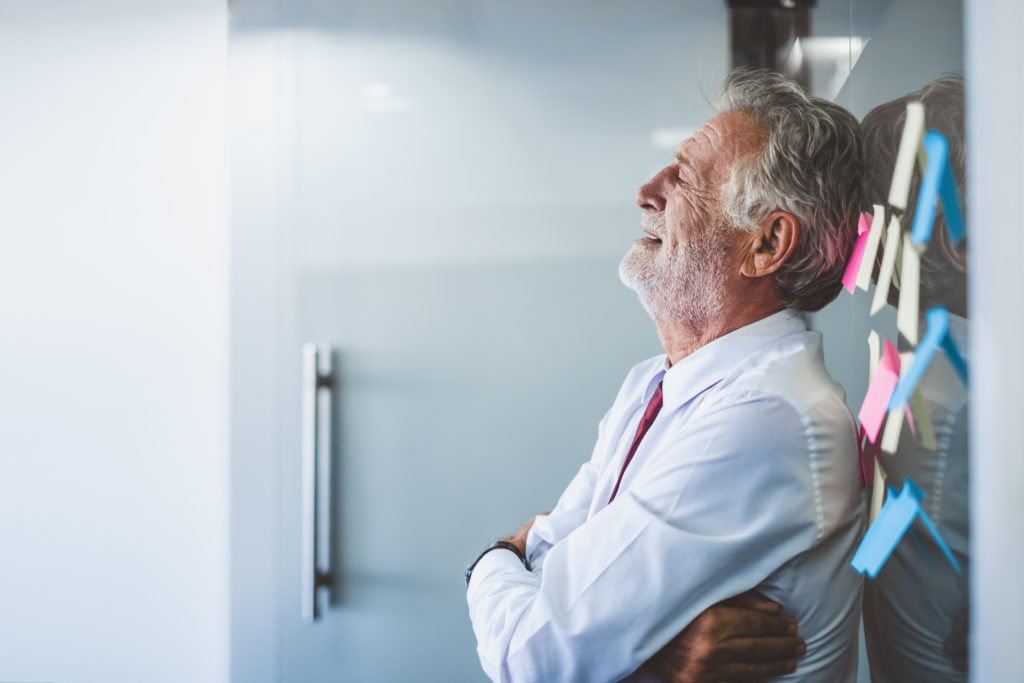 Old man leaning against the wall at his office after being suffering AgRETALIATION