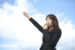 Woman blowing the whistle with arm raised in the sky